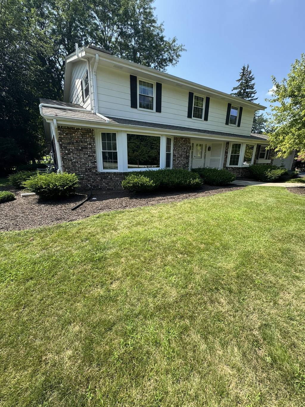 Mulched foundation beds and trimmed shrubs across the front of a two-story Waukesha County home