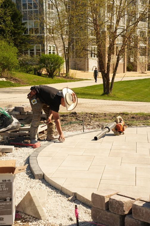 Crew member cleaning off a newly laid paver patio